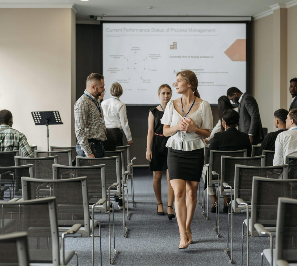 Professionals at a business conference engage before a presentation in a modern office.